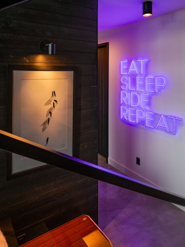 A modern glass-walled home illuminated at night with warm interior lighting, contrasting against the dark blue evening sky, showcasing a blend of ambient and accent lighting.